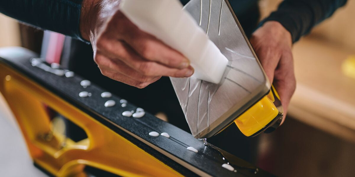 Wachs mithilfe eines Wachseisens auf den Ski auftropfen