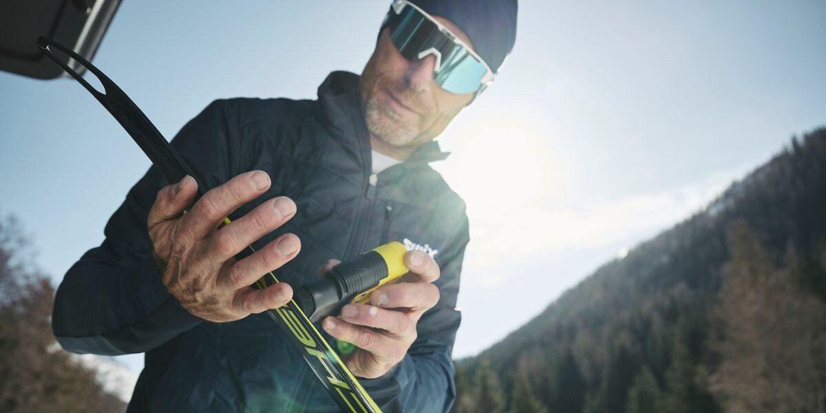 Mann wachst seine Ski vor dem Langlaufen