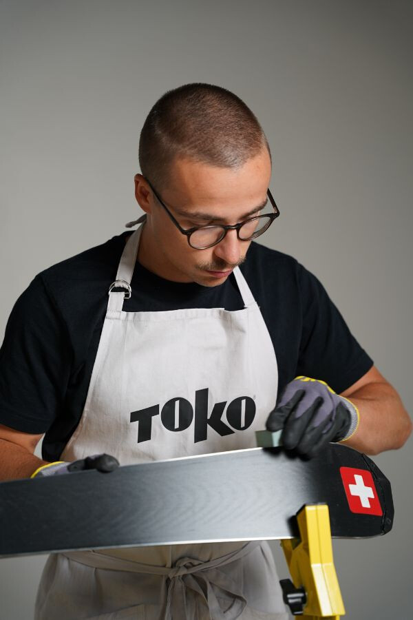 Mann begradigt eine Skikante